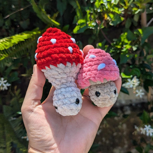 A red mushroom with its cap popped up beside a pink mushroom with its cap popped down. They are silent fidget toys.