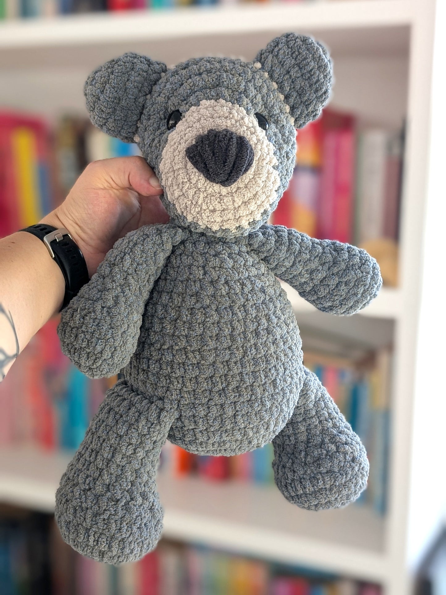A large crocheted bear toy in bluey-grey and beige colours