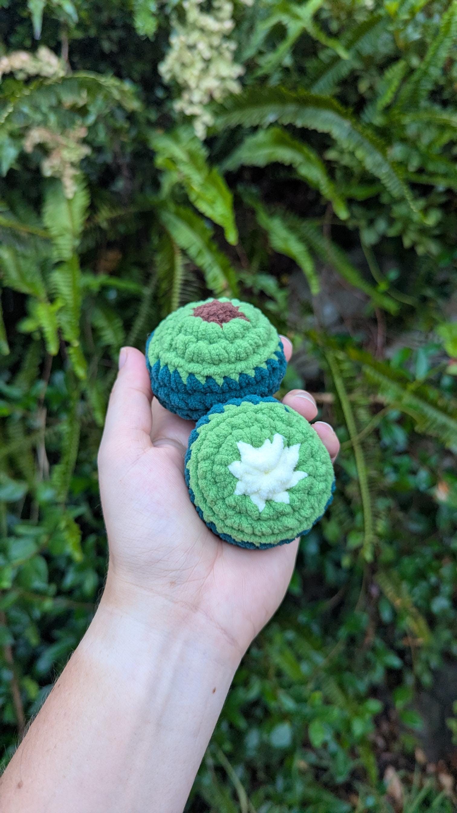A round crocheted avocado - one half with a seed and the other without