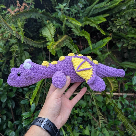 Side view of a purple crocheted dragon with yellow spikes and wing details, reminiscent of Spyro