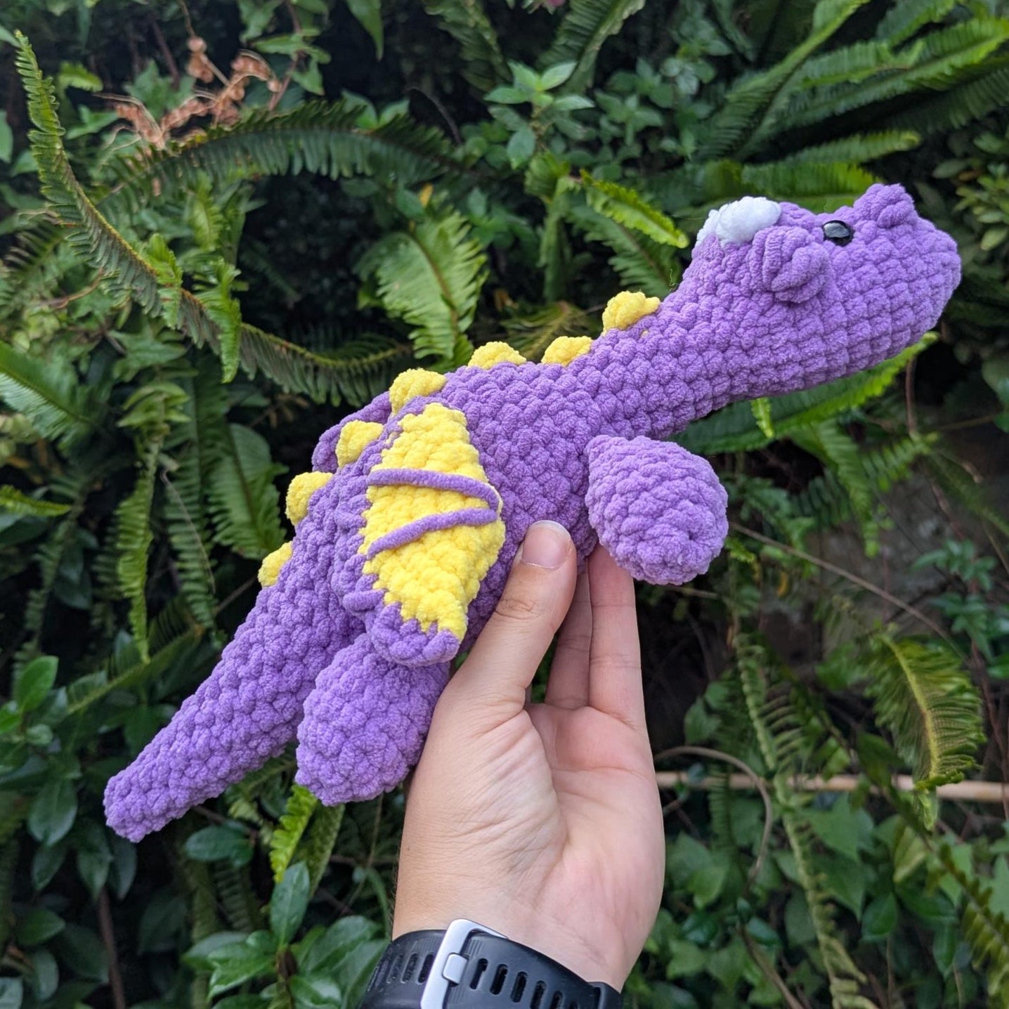 A purple and yellow crocheted dragon seen from the side